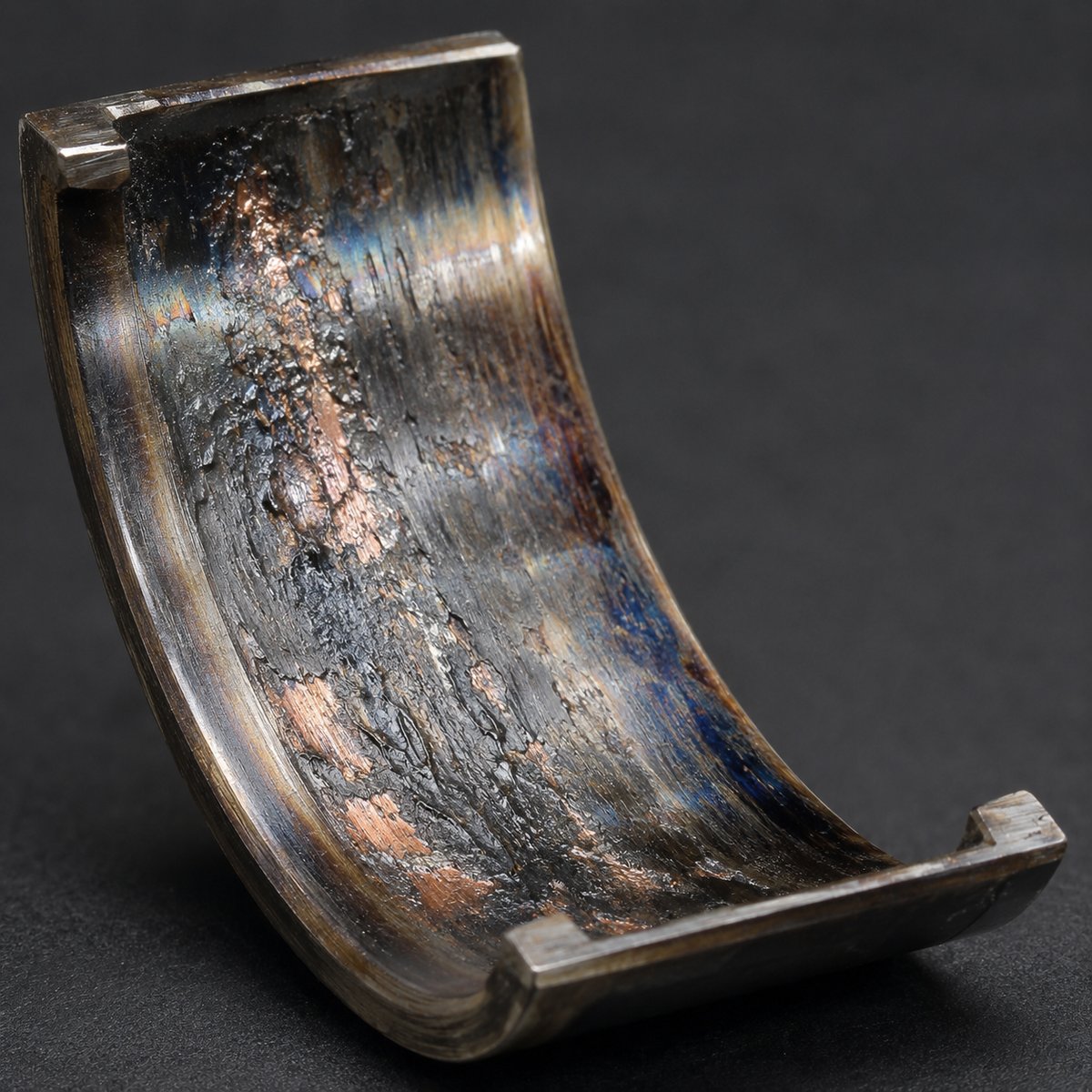 Bearing showing oil starvation damage — heat discoloration and exposed copper underlayer